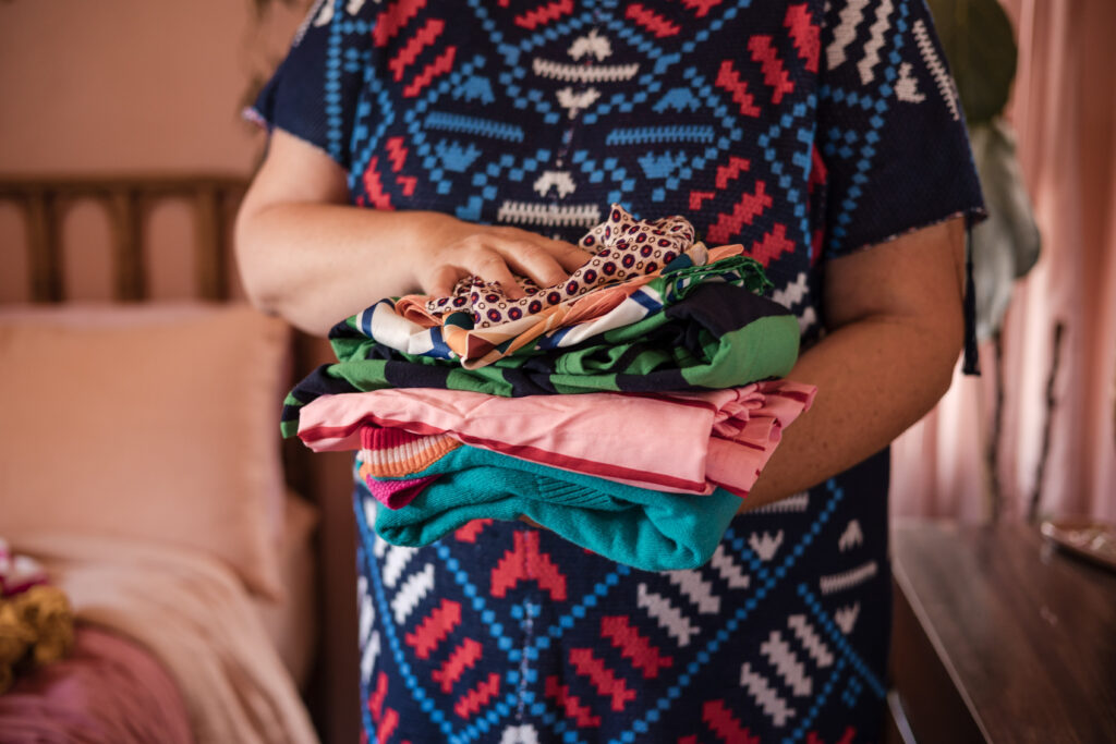 Neatly folded clothes in a cozy bedroom, organized by Go Goddess Organizing.
