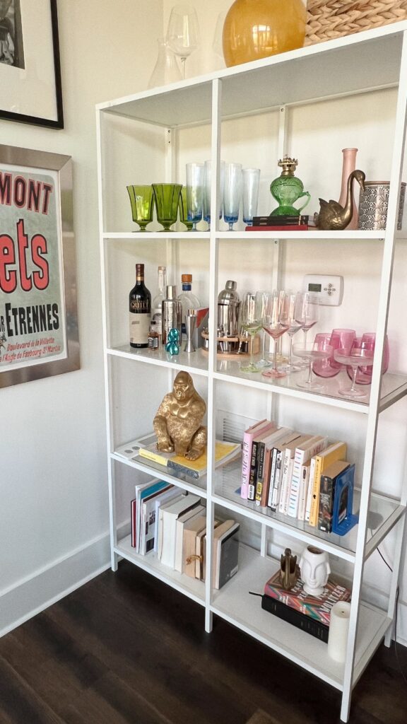 Organized home bar and bookshelf display by Go Goddess Organizing featuring glassware, books, decorative accents, and styled shelving in a modern living space.
